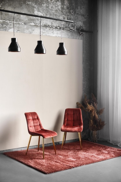 Zwei gemütliche rote Stühle stehen auf einem roten Teppich in einem leeren Raum. Vertikaler Rahmen Teil des Innenraums