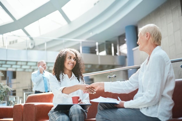 Zwei Geschäftsdamen, die sich in der Lobby des Business Centers die Hände schütteln