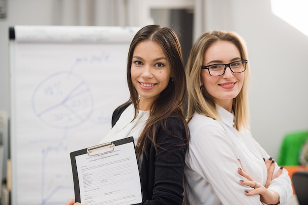 Zwei Geschäftsfrauen, die im Büro vor Flipchart stehen