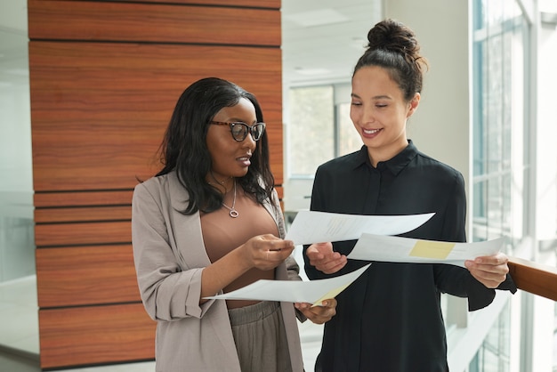 Zwei Geschäftsfrauen, die mit Dokumenten arbeiten und Verträge zusammen besprechen, während sie im Büro arbeiten