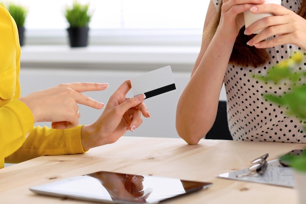 Zwei Geschäftsfrauen oder Freunde sprechen und verwenden einen Tablet-Computer.