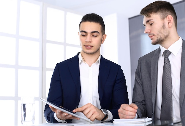 Zwei Geschäftsleute oder Partner, die mit einem Tablet-Computer am Schreibtisch im modernen Büro arbeiten