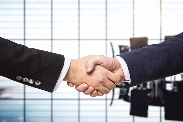 Zwei Geschäftsleute schütteln sich die Hände auf dem Hintergrund des sonnigen Konferenzraum-Deal-Konzepts aus nächster Nähe