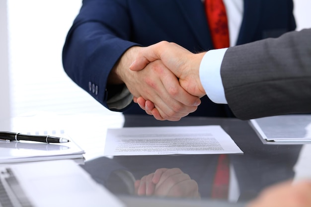 Zwei Geschäftsleute schütteln sich über dem unterzeichneten Vertrag die Hände