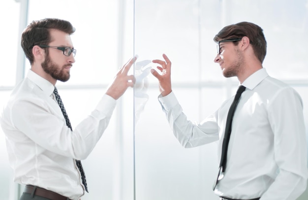 Zwei Geschäftsleute stehen in einem modernen Büro mit Glaswänden