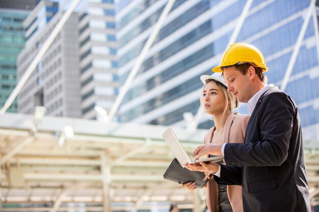 Zwei Geschäftsmänner und weibliche tragende Sicherheitswesten, die auf Baustelle sprechen und Händedruck