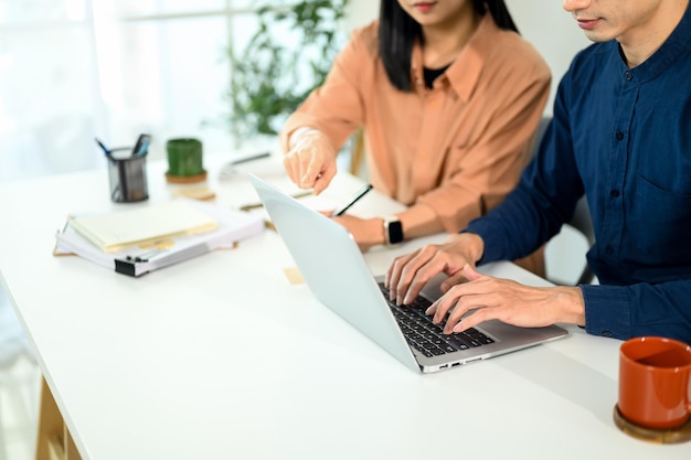 Zwei Geschäftspartner arbeiten zusammen an einem modernen Büro-Schreibtisch und analysieren Daten auf einem Laptop