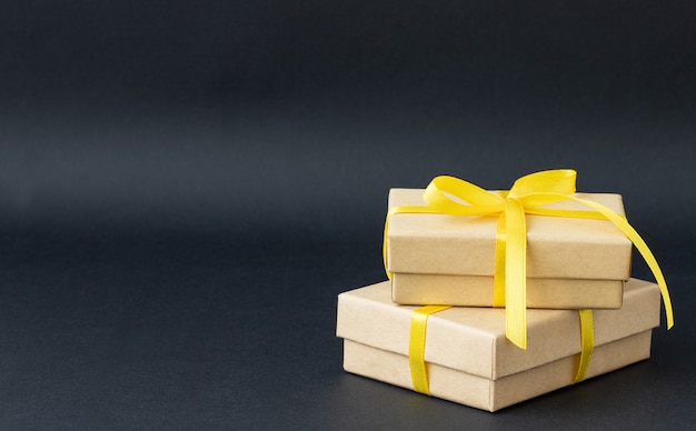 Zwei Geschenkboxen mit gelbem Band auf schwarzem Hintergrund