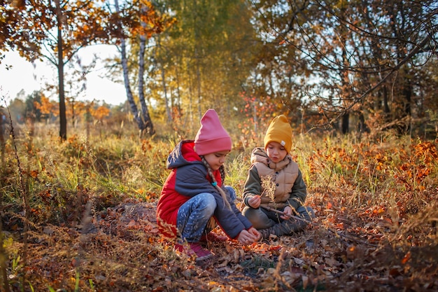 Zwei Geschwister ruhen sich während des Herbstspaziergangs im Herbstwald aus, ein aktives Familienwochenende im Freien