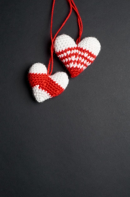 Zwei gestrickte handgemachte Valentinstagherzen auf dunklem Papier