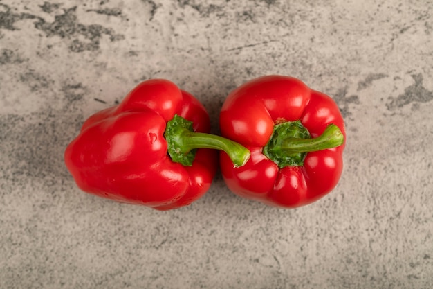 Zwei glänzende rote Paprika auf Steinoberfläche