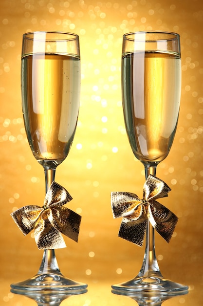 Zwei Gläser Champagner an heller Wand mit Lichtern