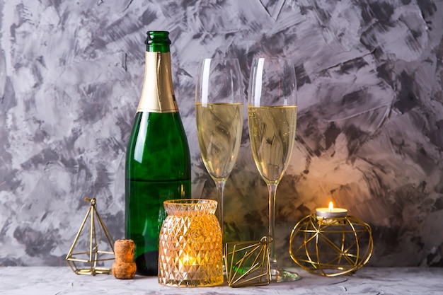 Zwei Gläser Champagner neben einer Flasche und goldfarbener Weihnachtsdekoration