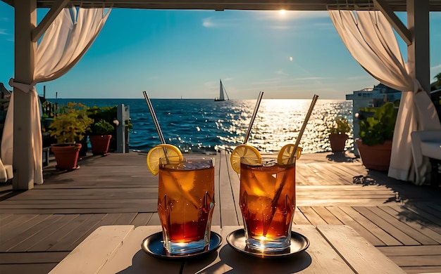 Zwei Gläser Eistee mit Zitrone und Stroh auf der Terrasse am Meer