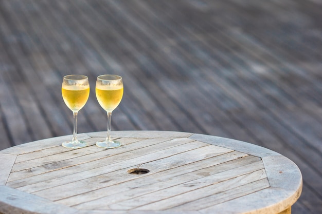 Zwei Gläser geschmackvoller Weißwein bei Sonnenuntergang auf Holztisch
