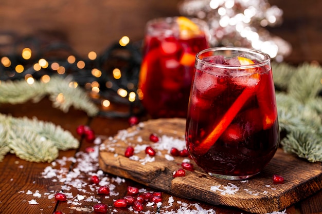 Zwei Gläser Granatapfelcocktail mit Orange auf dem Hintergrund von Weihnachtsdekorationen und