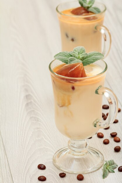 Zwei Gläser köstlicher Milchshake mit Schokoladeneis und Minzblättern auf grauem Holzhintergrund.