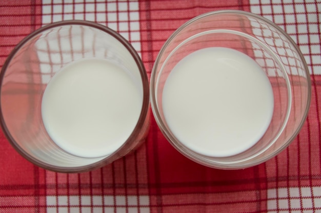 Zwei Gläser Milch stehen auf einer Draufsicht aus rot kariertem Stoff