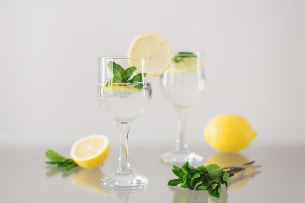Zwei Gläser Mineralwasser mit Zitrone und frischer Minze auf Glasoberfläche