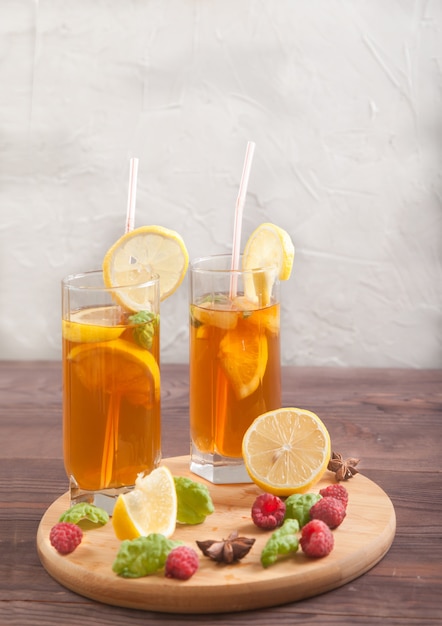 Zwei Gläser mit Cocktailröhre mit Kombucha- und Zitronenscheiben, Strohhalmen und Sternanis auf einem Holztisch.