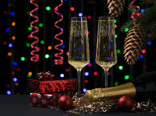 Zwei Gläser mit einer Flasche Champagner, Geschenken und einem Weihnachtsbaum