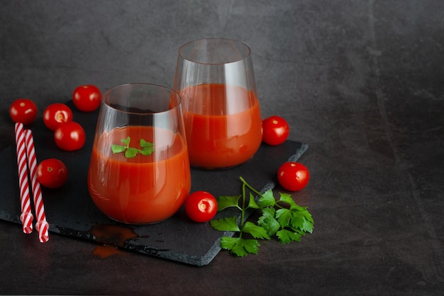 Zwei Gläser mit frischem Tomatensaft, Sellerie, Petersilie und reifen Tomaten