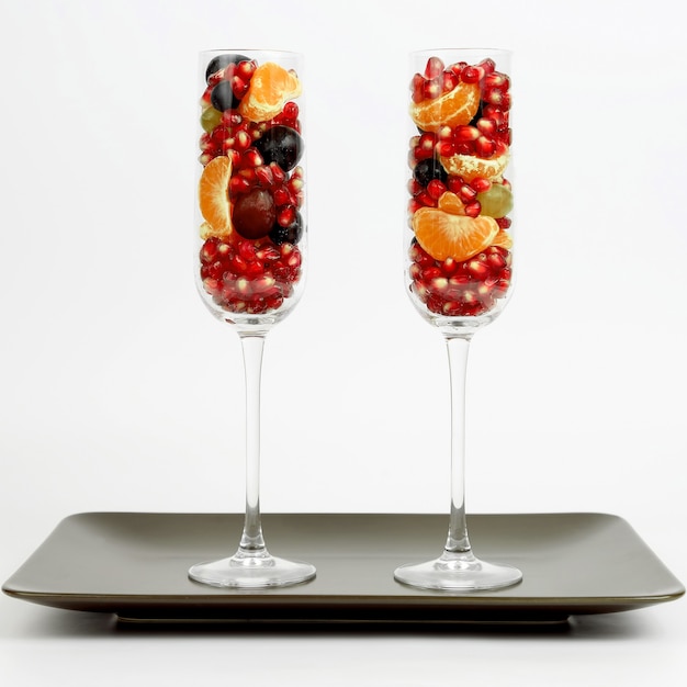 Zwei Gläser mit Früchten auf braunem Teller auf weißem Hintergrund. gesundes frisches Gemüse und Lebensmittel
