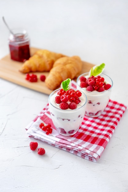 Zwei Gläser mit griechischem Joghurt, Himbeere und roter Johannisbeere