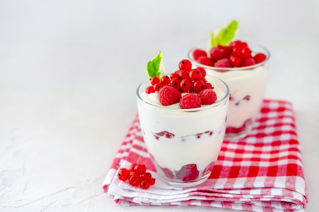 Zwei Gläser mit griechischem Joghurt, Himbeere und roter Johannisbeere.