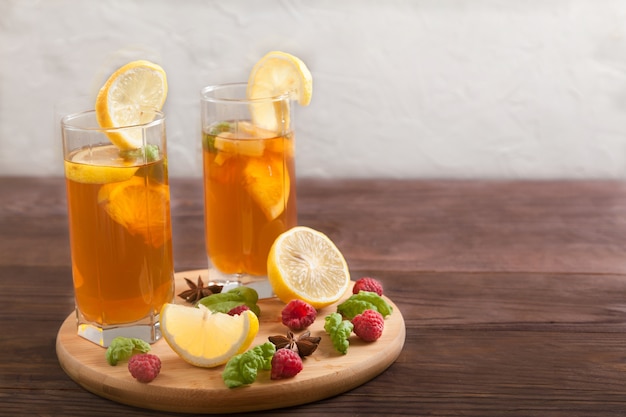 Zwei Gläser mit Kombucha- und Zitronenscheiben und Sternanis auf einem Holztisch.