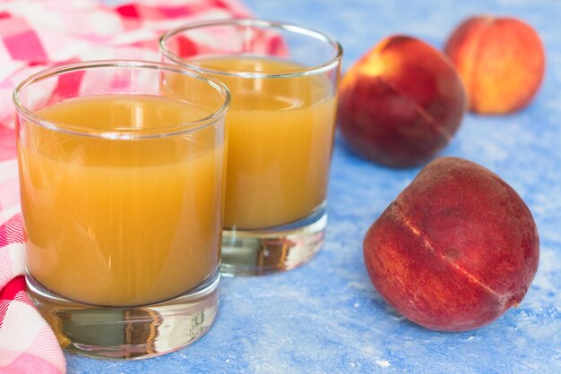 Zwei Gläser mit Pfirsichsaft auf blauem Hintergrund Nahaufnahme