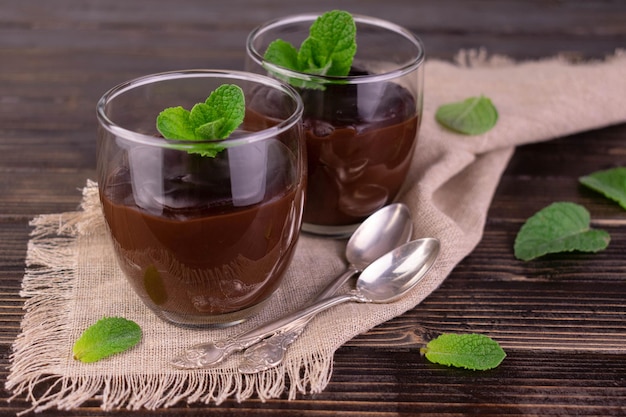 Zwei Gläser mit Schokoladendessert auf dunklem HolzhintergrundSchokoladenpudding