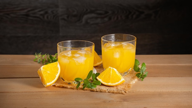 Zwei Gläser Orangensaft mit Minze und Orange auf dem Tisch
