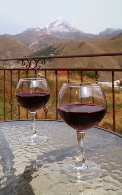 Zwei Gläser Rotwein auf einem Glastisch mit dem schneebedeckten Berg im Hintergrund