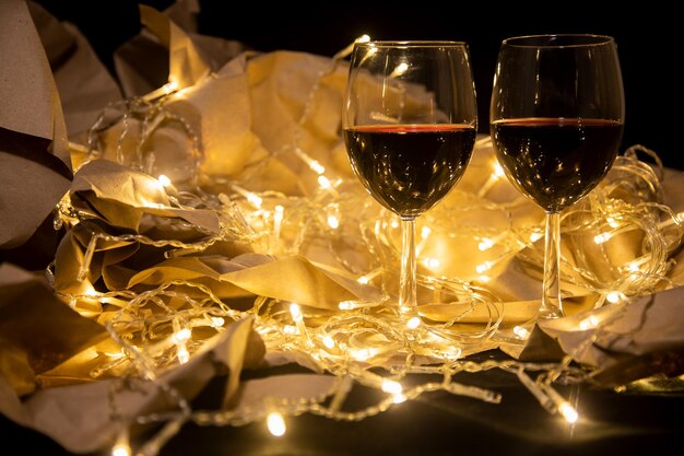 Zwei Gläser Rotwein stehen in einer leuchtenden Girlande