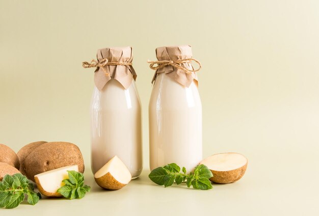 Zwei Glasflaschen mit veganer Pflanzenmilch aus Kartoffelknollen auf beigem pastellfarbenem Hintergrund das Konzept eines gesunden Ernährungsgetränke-Ersatzes