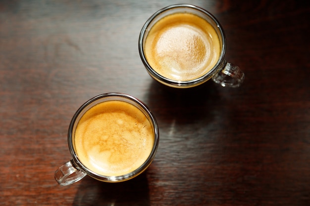 Zwei Glaskaffeetasse mit Espresso am Fenster morgens auf dunklem Hintergrund