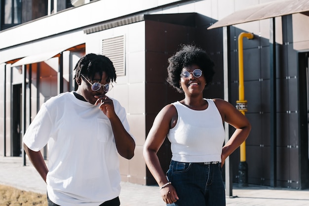 Zwei glückliche afroamerikanische Frauen gehen im Sommer die Straße entlang.