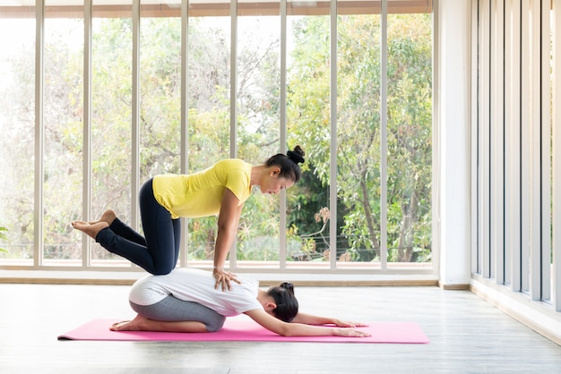 Zwei glückliche asiatische Frauen in Yoga-Posen im Yoga-Studio mit natürlicher Lichteinstellungsszene / Übungskonzept / Yoga-Praxis / Kopierraum / Yoga-Studio