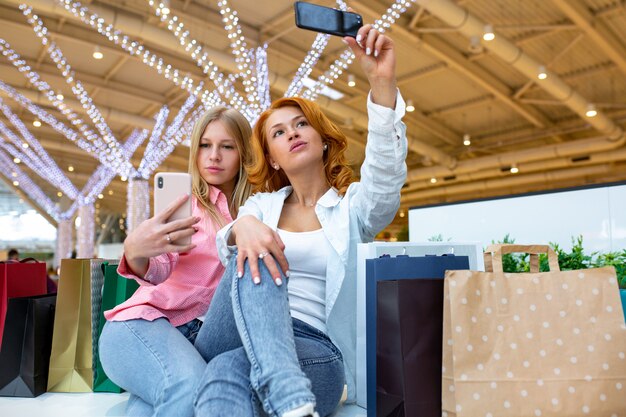 Zwei glückliche Freunde machen Selfie beim Einkaufen im Einkaufszentrum.