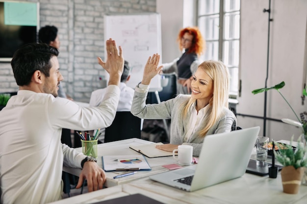 Zwei glückliche Geschäftsleute, die nach einem erfolgreichen Job Highfive geben und Spaß bei der Arbeit haben. Der Fokus liegt auf der Geschäftsfrau