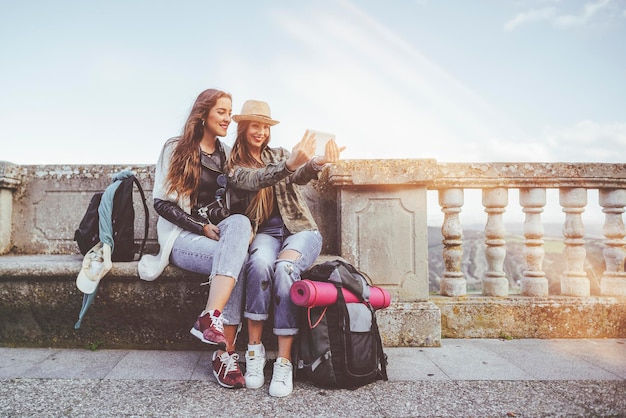 Zwei glückliche junge Frauen machen auf einer Reise ein Selfie mit einem Tablet