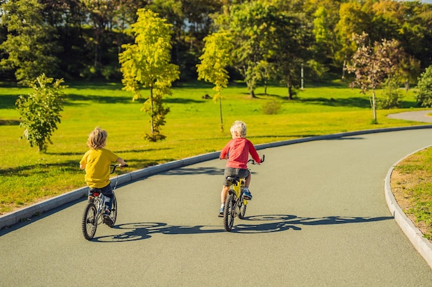 Zwei glückliche Jungs, die im Park radeln