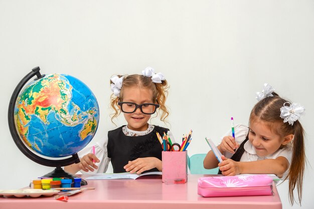 zwei glückliche kleine Mädchen lernen und schreiben in der Klasse isolieren