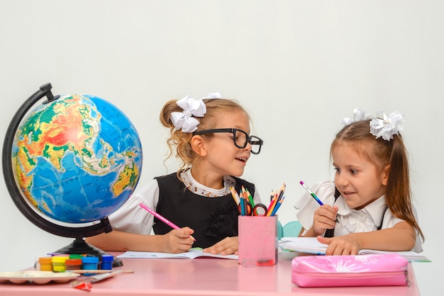 zwei glückliche kleine Mädchen lernen und schreiben in der Klasse isolieren