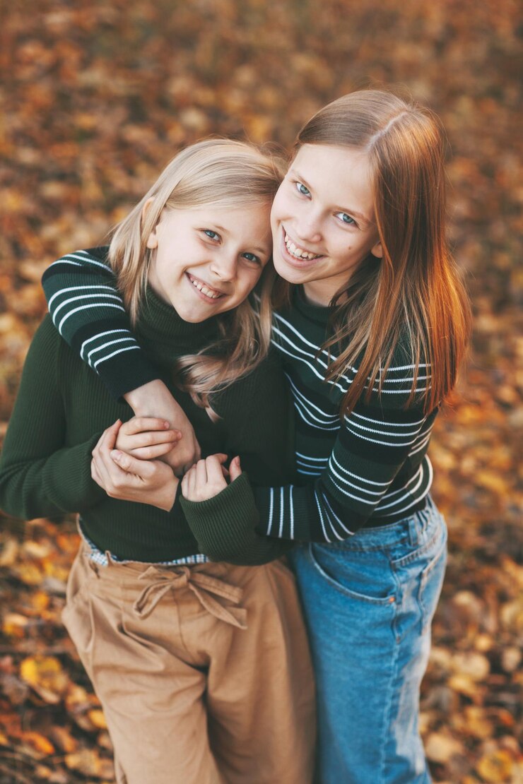 Foto zwei glückliche kleine schwestern lachen, haben spaß und spielen im herbst in der natur im freien