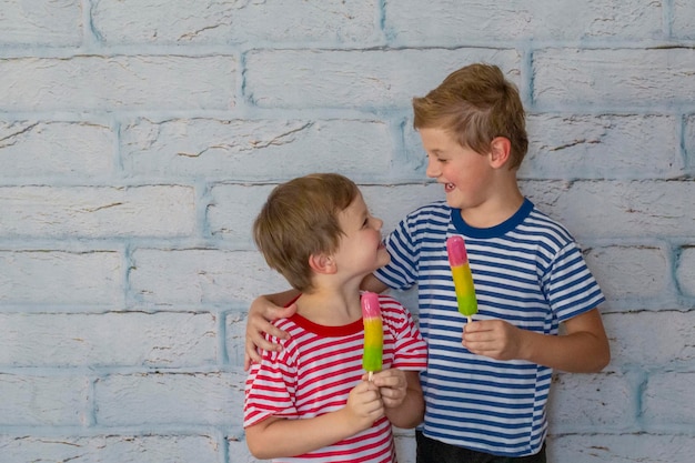 Foto zwei glückliche lächelnde jungen essen eis. kinder, die sich umarmen, essen gefrorenes fruchteis