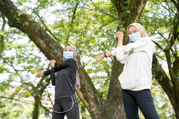 Zwei glückliche muslimische Freundin trainieren zusammen und tragen eine Maske für den Schutz vor Viren