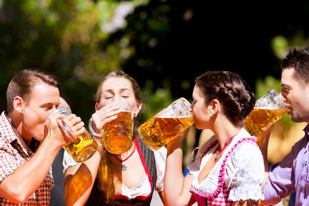 Zwei glückliche Paare, die im Biergarten sitzen