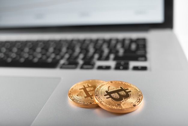 Zwei goldene Bitcoins auf silberner Laptoptastatur